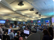 Large room full of people looking at big screens with information about the storm